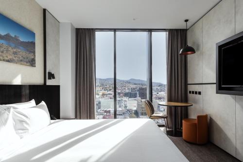 a hotel room with a bed and a large window at Mövenpick Hotel Hobart in Hobart