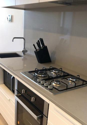 a kitchen with a stove top oven in a kitchen at Cozy 1 Bedroom Apt Parkside Pool Gym Parking close CBD in Melbourne