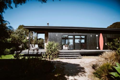 a black house with a large window and a patio at Sheoakes Beach House- East Coast Tas in Falmouth