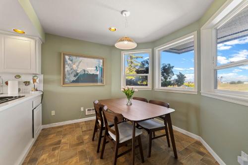 a kitchen with a table and chairs and windows at SANDY POINT 6 BEDS 3 BATHS BEACH HOUSE WITH AMAZING VIEWS in Ferndale