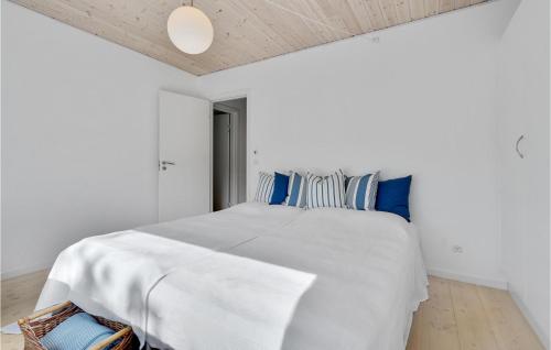 a white bedroom with a large bed with blue pillows at Holiday Home Stubbekobing With Fireplace I in Ore