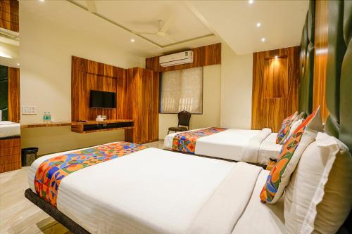 a hotel room with two beds and a television at FabHotel Prime Majhali in Nashik