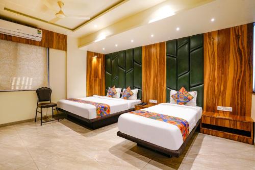 a hotel room with two beds and a chair at FabHotel Prime Majhali in Nashik