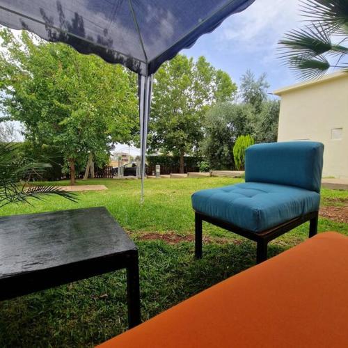 a blue chair and a table and an umbrella at Villa Joudia Royal Golf Fes in Fès