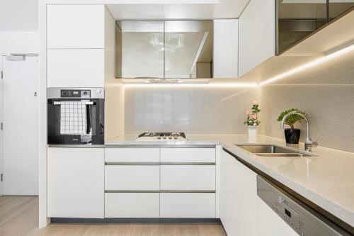 a kitchen with white cabinets and a sink at ChinatownICCHaymarket Adorable 2Br Apt at CBD in Sydney