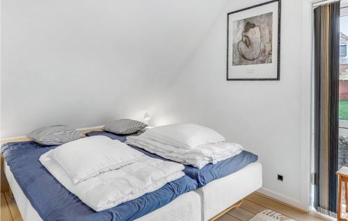 a white bedroom with a bed with blue and white pillows at 2 Bedroom Cozy Apartment In Svaneke in Svaneke