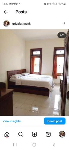 a bedroom with a bed and two windows at Griya Fatima in Kejayan