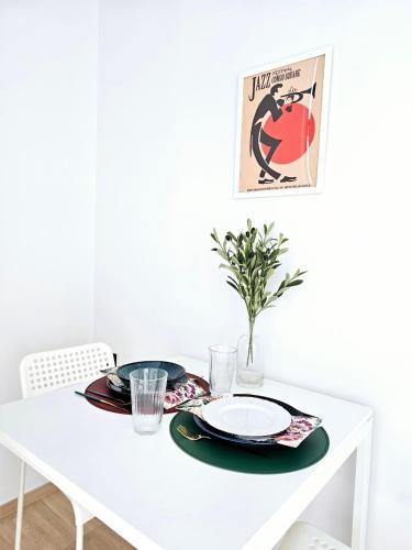 a white dining room table with a tablecloth and plates and a poster at Midtown Duplex Ratchayothin in Bangkok