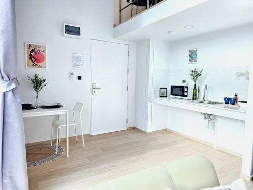a white living room with a table and a microwave at Midtown Duplex Ratchayothin in Bangkok