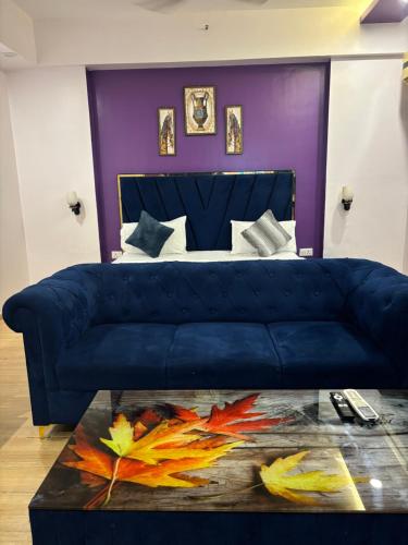 a blue couch in a room with a bed at The Royal Suites Gomti Nagar Lucknow in Lucknow