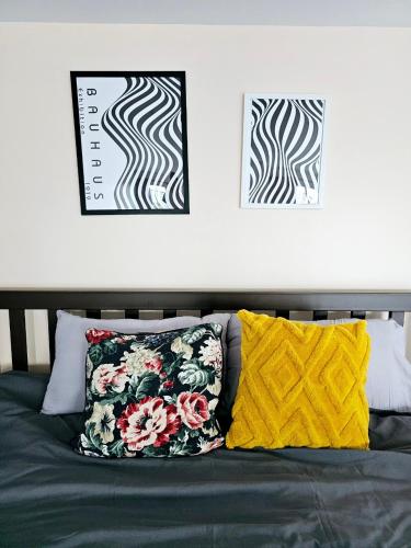 a bed with two pillows and two pictures on the wall at Midtown Duplex Ratchayothin in Bangkok