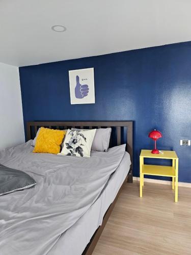 a bed with a blue wall and a yellow table at Midtown Duplex Ratchayothin in Bangkok