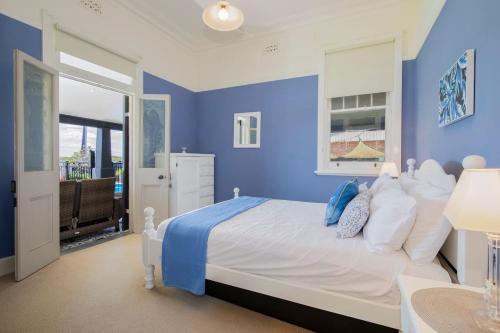 a blue bedroom with a large bed with blue walls at Ludford Lakefront & Beachside Retreat for Groups in Swansea