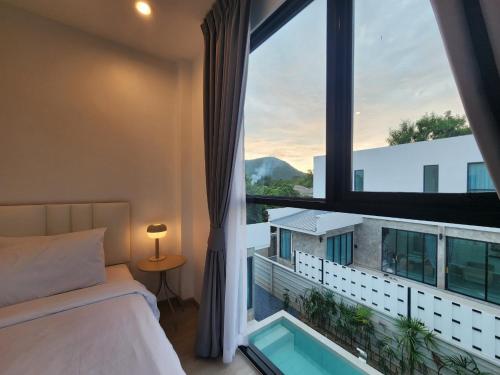 a bedroom with a bed and a window with a swimming pool at Gina Poolvilla90 Pattaya-Bangsaray to beach 900M in Bang Sare