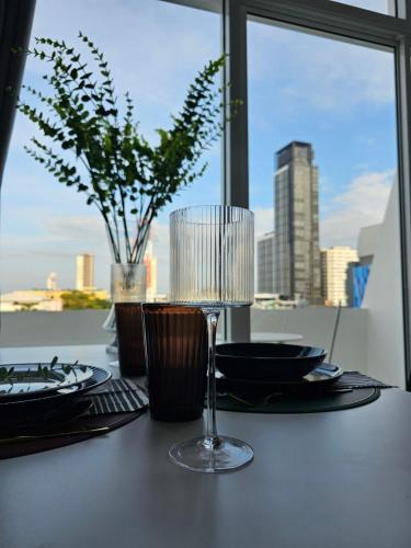 a table with a wine glass on a table with a view at Midtown Duplex Ratchayothin in Bangkok