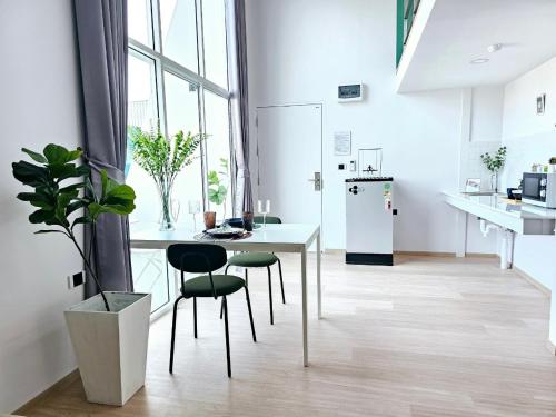 a white kitchen with a white table and chairs at Midtown Duplex Ratchayothin in Bangkok