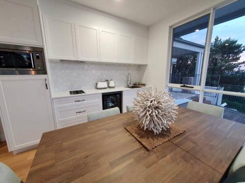 a kitchen with a wooden table and a kitchen with white cabinets at Wake up to the ocean at LegaSea in Shellharbour