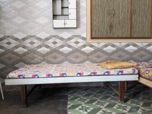 a bed sitting in a room with a wall at 20 minutes from City - Village Home in Ahmedabad