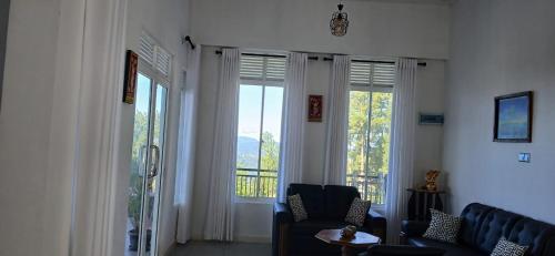 a living room with a couch and two large windows at Ama Residency & Homestay Kandy in Hindagala