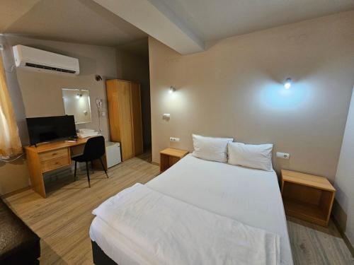 a bedroom with a bed and a desk and a television at Hotel Racic Self-Check In in Voyvodinovo