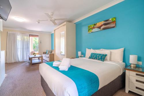 バイロンベイにあるByron Bayside Central Studio Apartmentsの青い壁のベッドルーム1室(大型ベッド1台付)