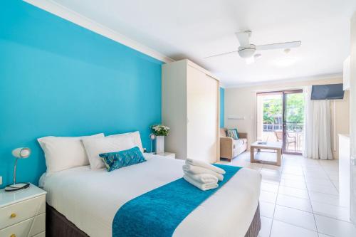 a bedroom with a large bed with a blue wall at Byron Bayside Central Studio Apartments in Byron Bay