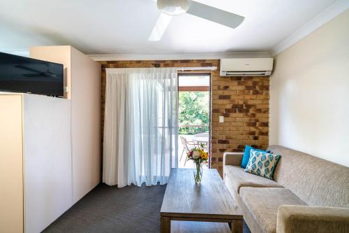 a living room with a couch and a table at Byron Bayside Central Studio Apartments in Byron Bay