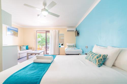 a bedroom with a large white bed with blue accents at Byron Bayside Central Studio Apartments in Byron Bay