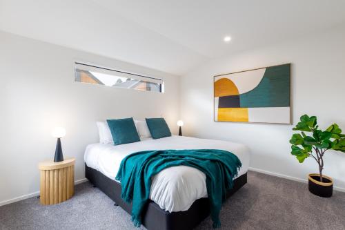 a bedroom with a large bed with blue pillows at Chatham Street - Christchurch Holiday Homes in Christchurch