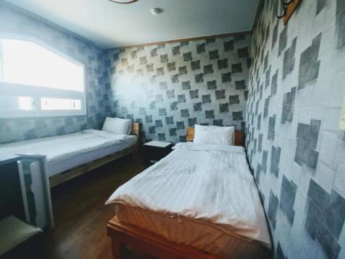 a bedroom with two beds and a tv in it at Shiny Hotel in Jeju