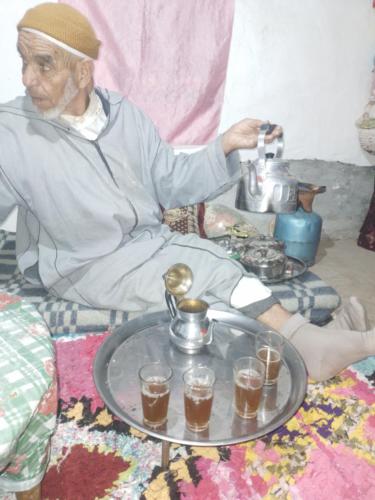 a man sitting on a couch with a table with a tea kettle at Riad Dar Amgdoule Tacheddirt in Tacheddirt