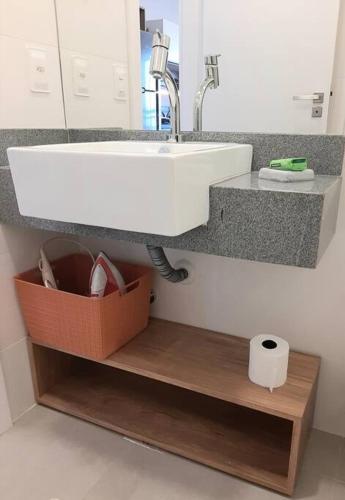a bathroom with a sink and a roll of toilet paper at Studio Xavante 615A - com garagem, portaria 24h e uma vista linda! in Pelotas