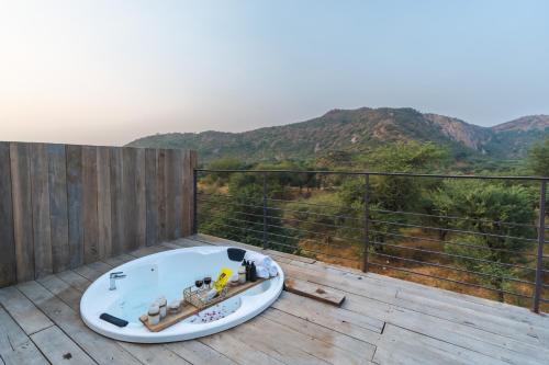 a bath tub sitting on a deck with a view of mountains at Teela- The Glamping Resort, Jaipur in Udāsar