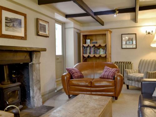 - un salon avec un fauteuil en cuir et une cheminée dans l'établissement Thorn Cottage, à Spark Bridge