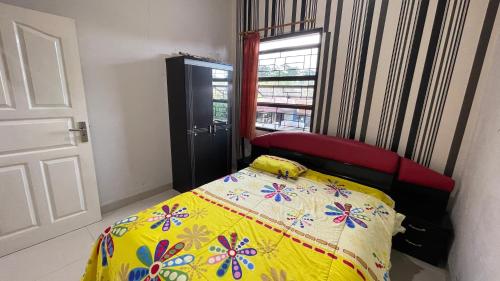 a bedroom with a bed with a yellow blanket and a window at Guest House Pesona Alam in Cijoho