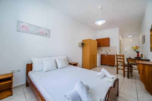 a bedroom with a white bed and a kitchen at Ancient Thera Apartments in Kamari