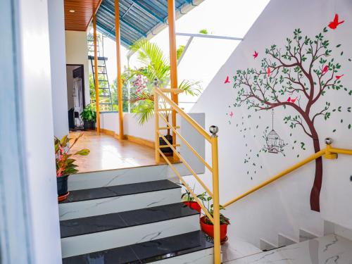 a staircase with a mural of a tree and birds at Marari Eden Castle in Vayalār