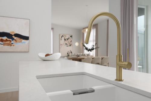 a white kitchen with a sink and a gold faucet at Bella Villa in Safety Beach
