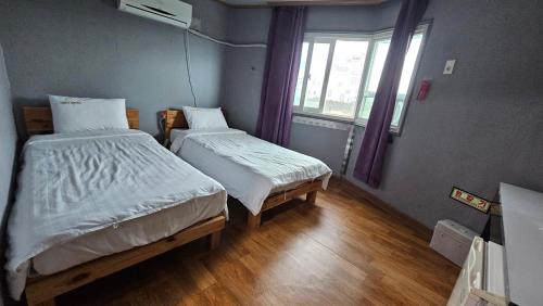 a small room with two beds and a window at Shiny Hotel in Jeju