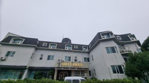 a large white building with a sign that reads shiny hotel at Shiny Hotel in Jeju
