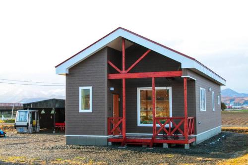 a small house with red accents on it at Furano Cottage Shelter in Nakafurano