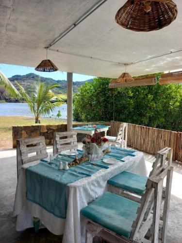 a table with a blue tablecloth and chairs under a white umbrella at La Case Du Pecheur in Grand Sable