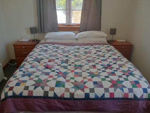 a bed with a quilt on it in a bedroom at Comfortable home on South Hill in Oamaru