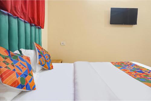 a bedroom with a white bed with colorful pillows at FabHotel New Falcon Inn - Nr Balewadi stadium in Pune