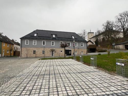 a large white house with a black roof on a street at Ferienwohnungen Yanev in Oberkotzau