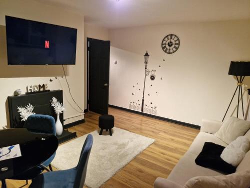 a living room with a couch and a clock on the wall at Elegant & Spacious 2-Bedroom Apartment in Wimbledon in London