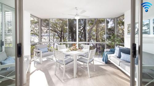 a dining room with a table and chairs and windows at Belvedere Bayfront in Nelson Bay