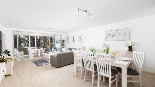 a white living room with a table and chairs at Belvedere Bayfront in Nelson Bay