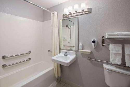 a bathroom with a sink and a tub and a toilet at Days Inn & Suites by Wyndham Green Bay WI in Green Bay