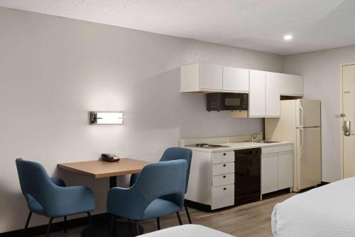 a small kitchen with a table and blue chairs at Days Inn & Suites by Wyndham Green Bay WI in Green Bay